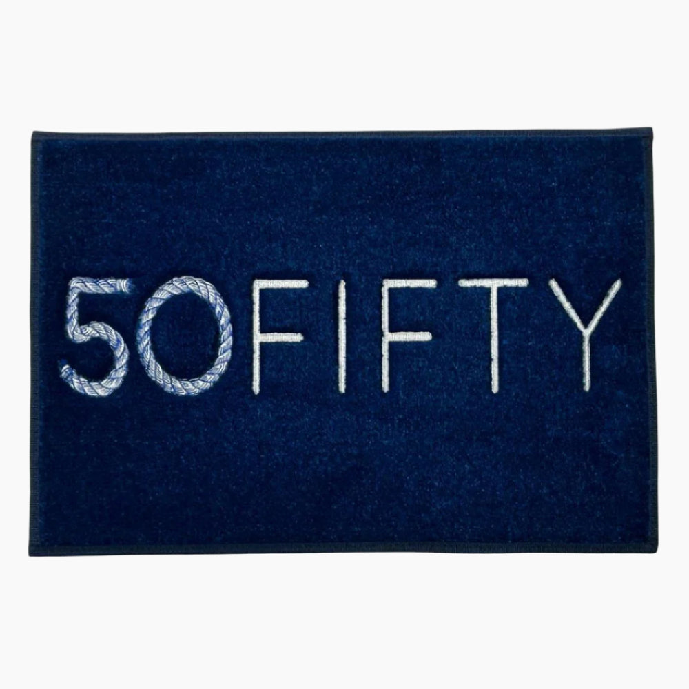 A navy blue marine carpet boat mat with the word '50FIFTY' embroidered in white. Custom embroidered logo mat for luxury yacht dock