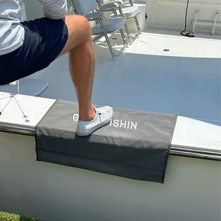 Person stepping onto a boat with a custom gunnel boarding mat that says "gone fishin" on a sunny day.