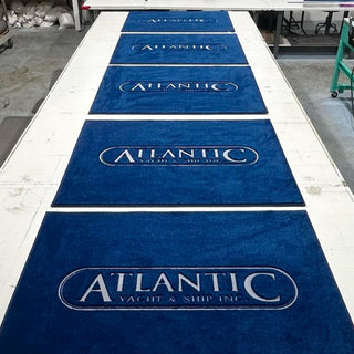 A personalized embroidered carpet boat mat with the custom logo 'Atlantic' displayed prominently in a manufacturing setting at our location in Fort Lauderdale, Florida