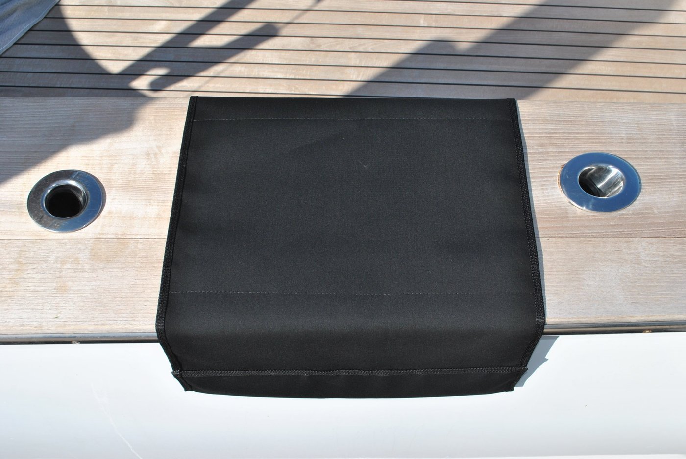 Plain black Sunbrella® boarding mat draped over yacht gunwale on teak deck — BoatMat Corporation