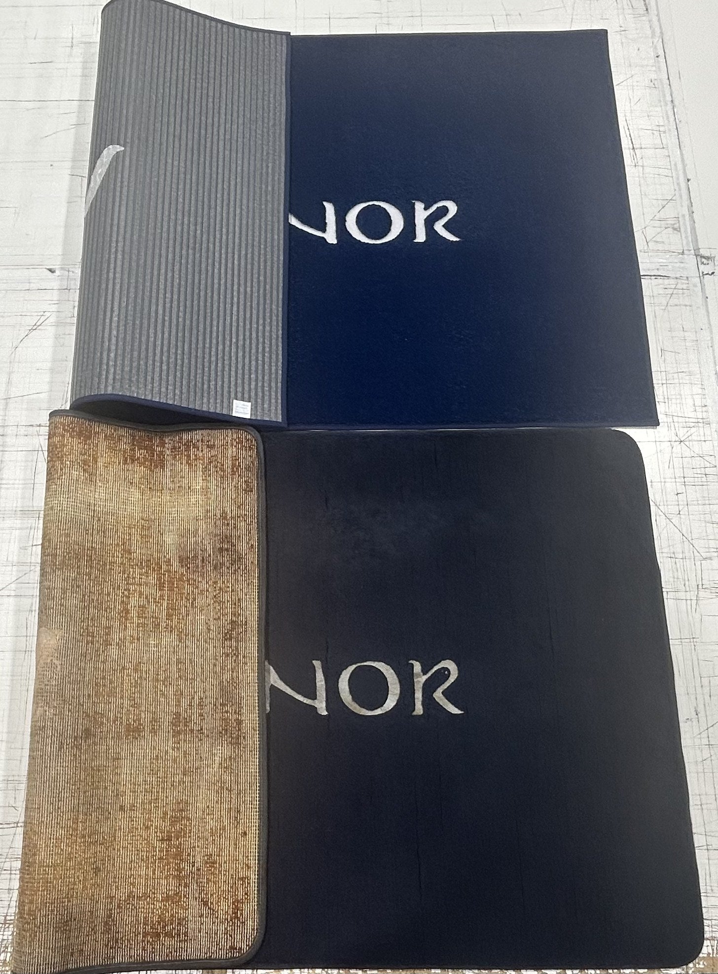 Same vessel name — BoatMat Corporation product with intact backing on top vs competitor with completely deteriorated brown backing on bottom